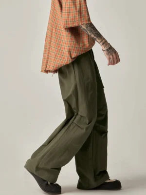 Green drawstring wide leg cargo pants rear three quarter view with lightweight crinkled nylon streetwear fabric