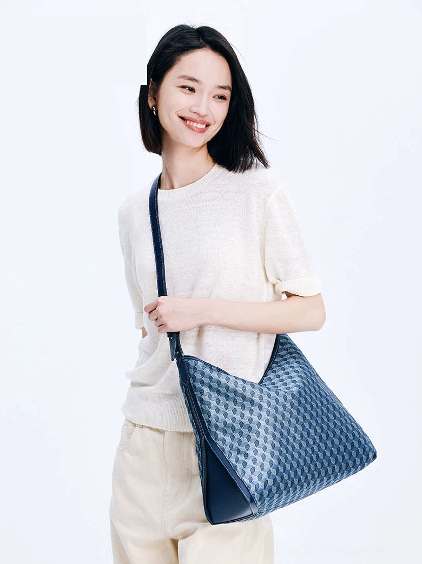 Model carrying spacious dusty blue monogram large hobo shoulder bag with white top and beige trousers