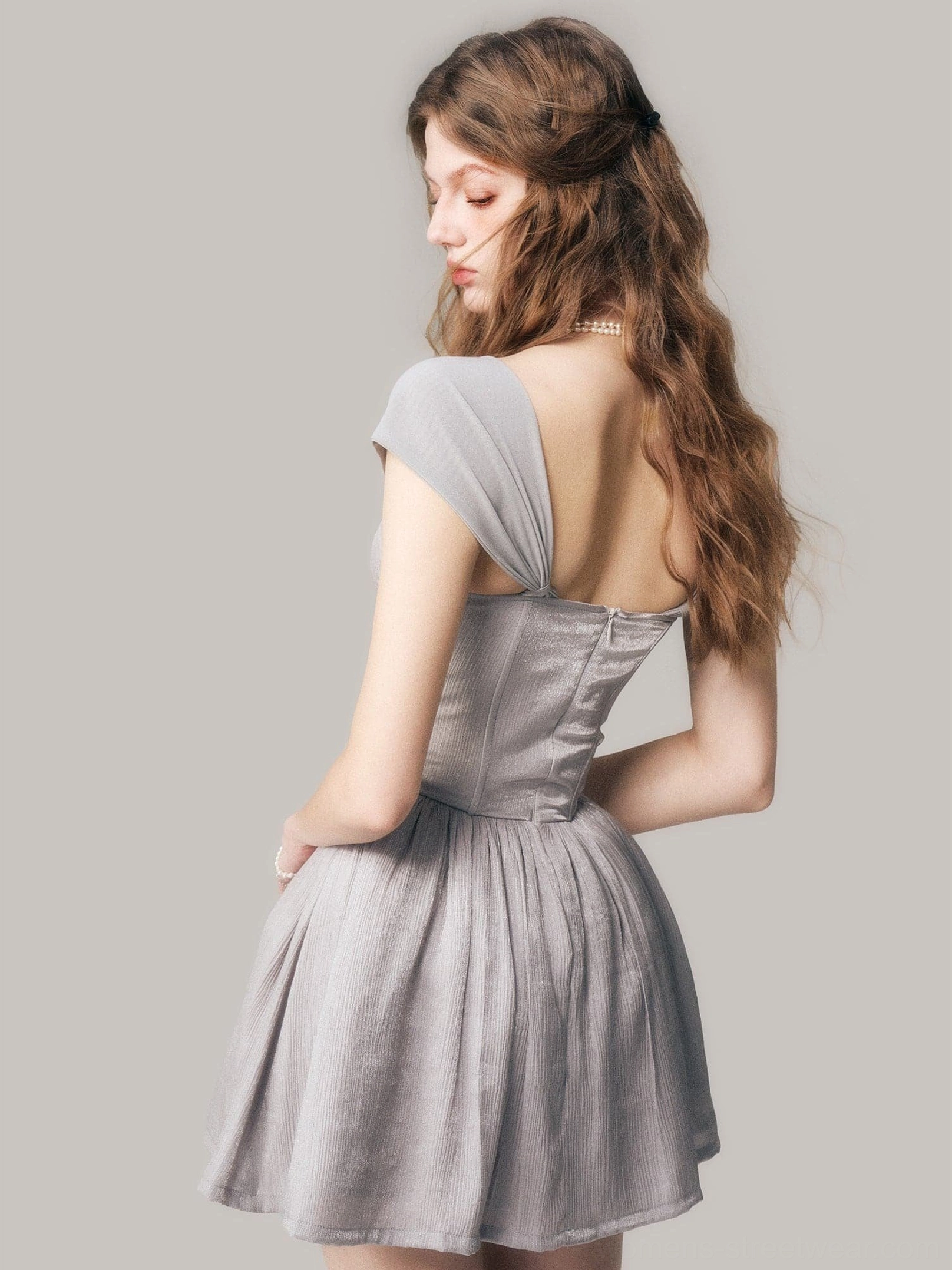 Rear three quarter view of a dusty gray backless corset mini dress with cap sleeves and flowing gathered skirt