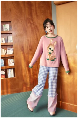 Side front view of dusty pink bunny graphic knit sweater with fuzzy texture, contrast ribbed cuffs, and colorful vintage Korean streetwear styling