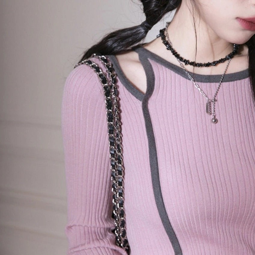 Close-up of dusty pink ribbed knit top shoulder cutout dark gray trim and layered chain necklaces