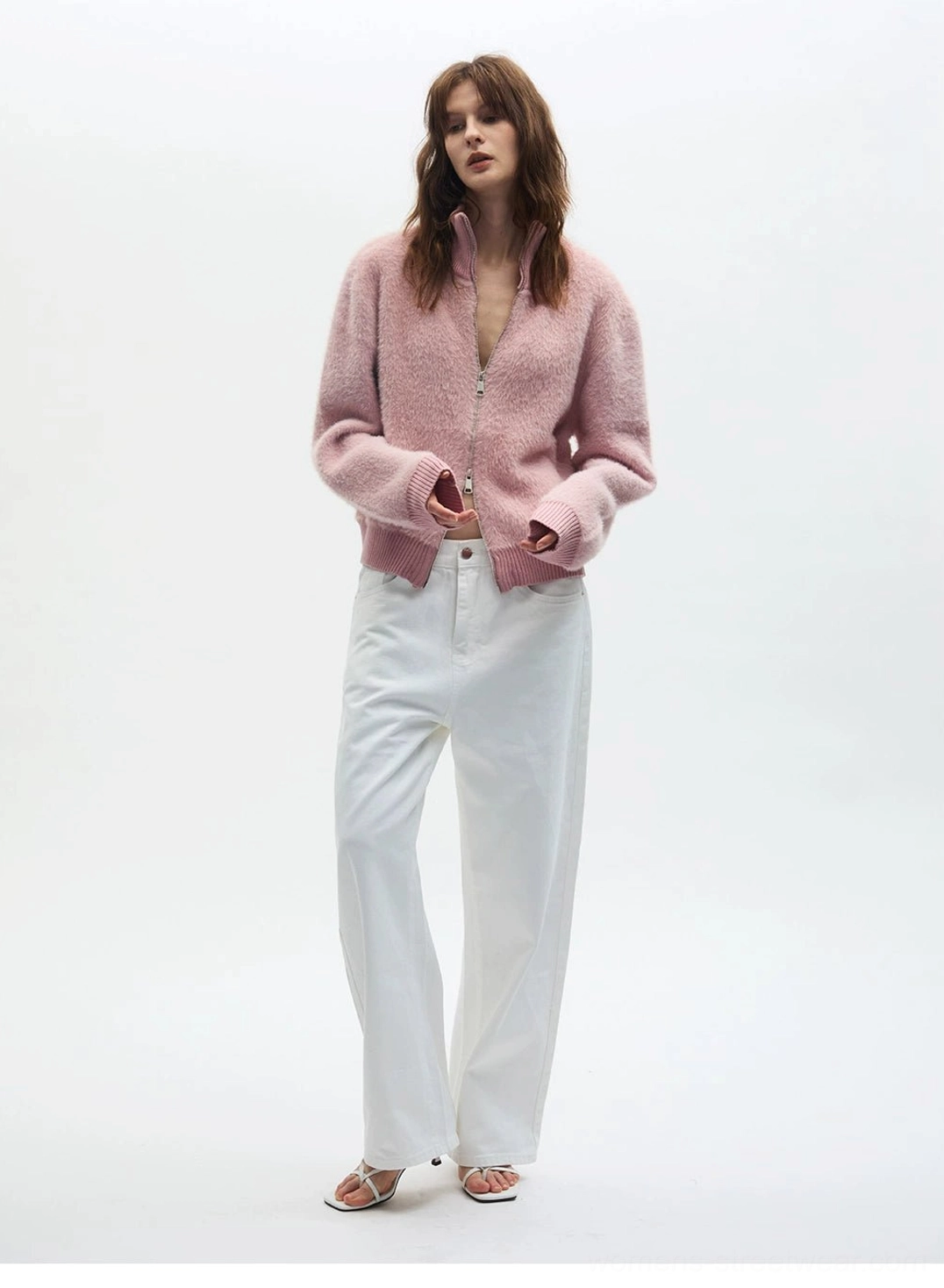 Dusty pink fuzzy zip-up fleece cardigan worn half unzipped with high-waisted white pants in full-body view