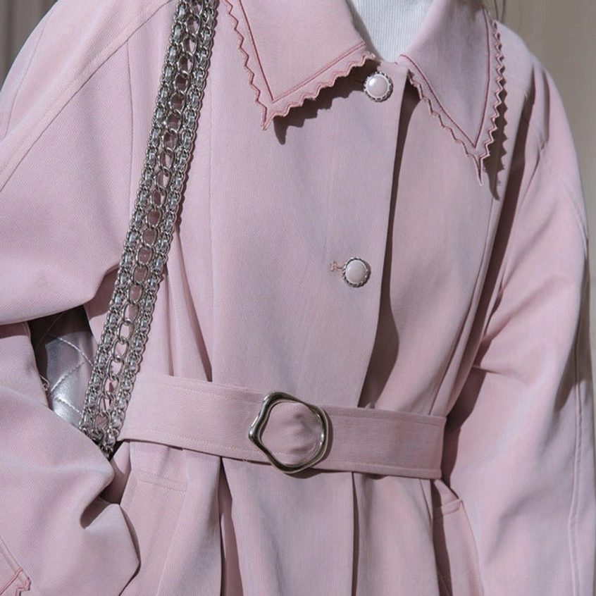 Close-up front view of scalloped collar round buttons and O-ring belt on dusty pink pleated trench coat