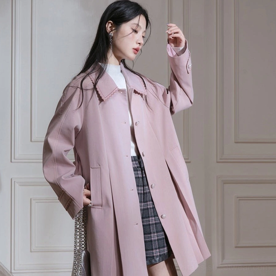 Side view of relaxed dusty pink scalloped collar trench coat styled with plaid mini skirt and chain bag