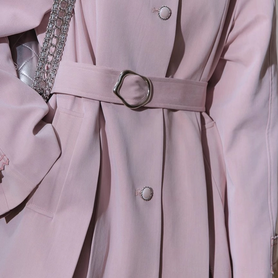 Close-up of O-ring adjustable waist belt round buttons and soft dusty pink fabric on pleated trench coat