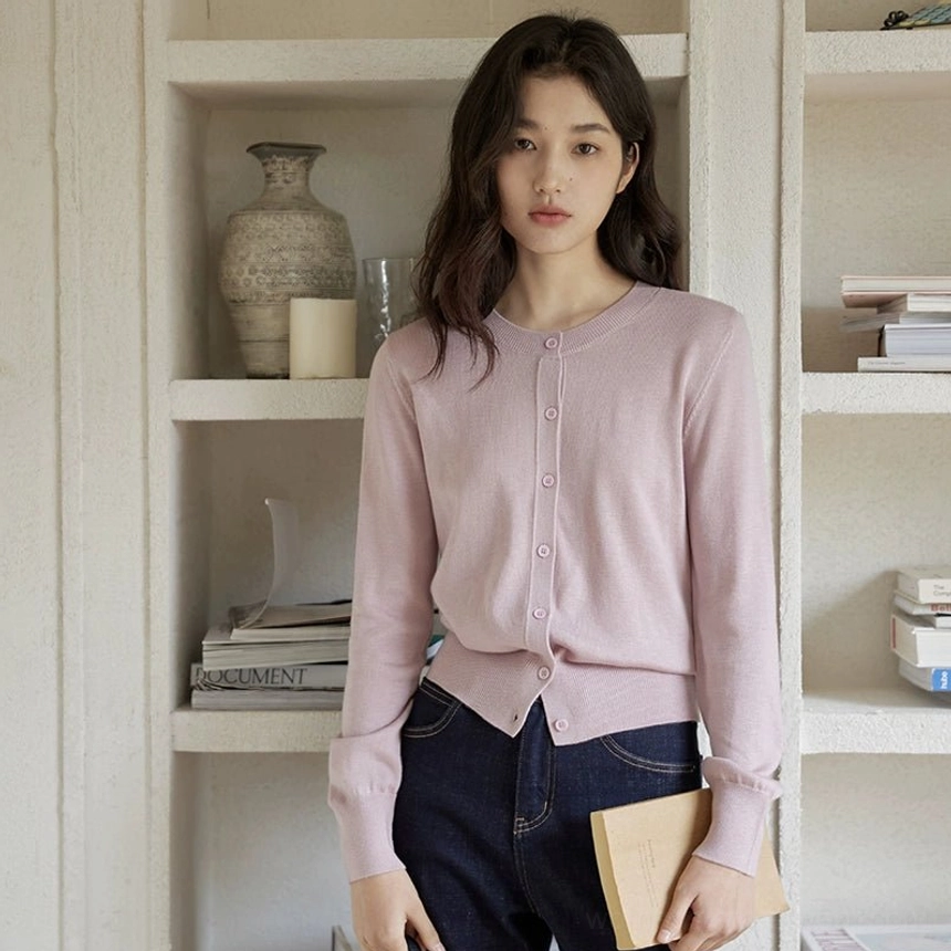 Dusty pink women's button-front knit cardigan with structured placket styled with dark jeans and a shoulder bag