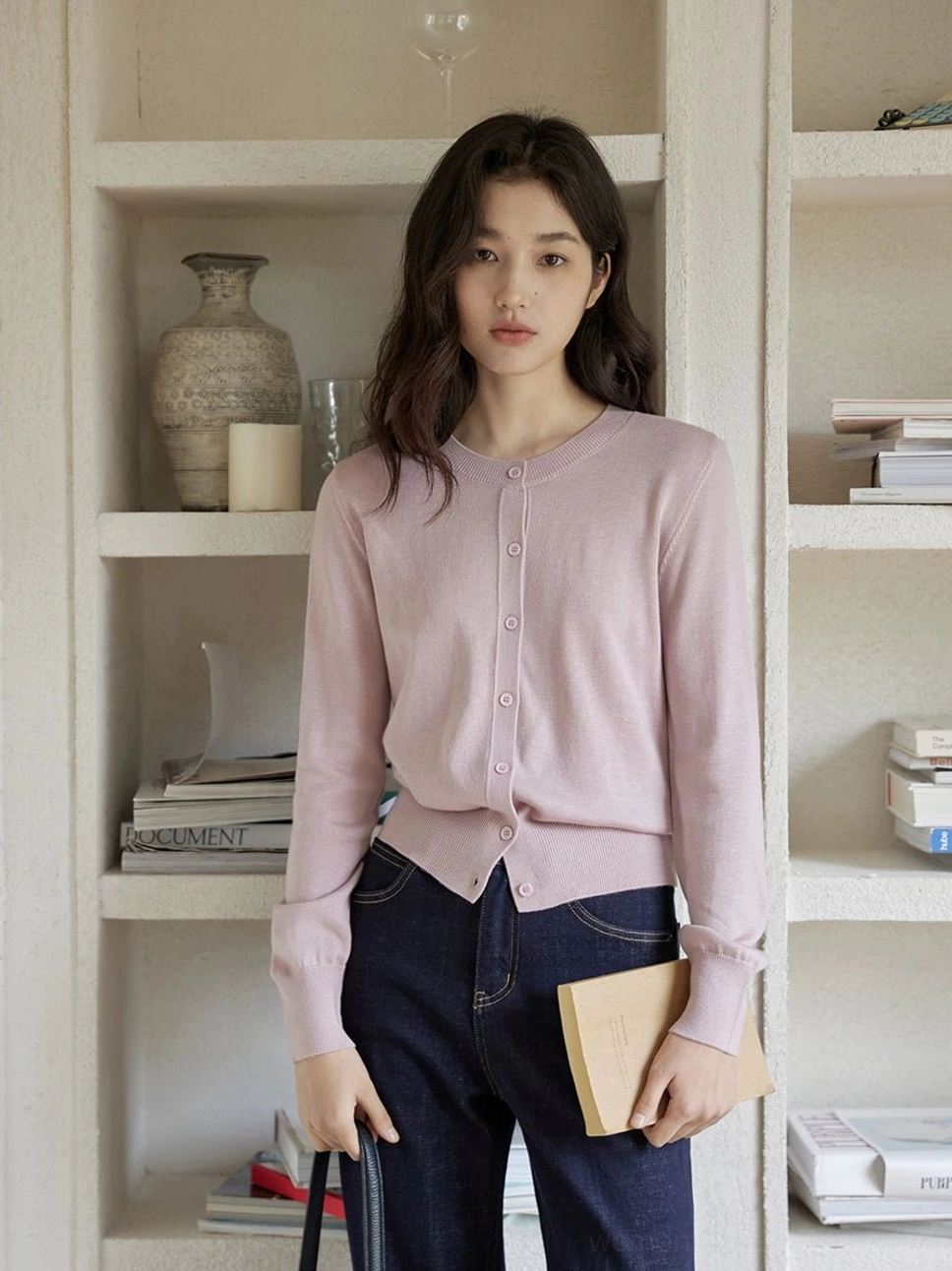 Dusty pink women's cropped crew neck cardigan with neat front buttons styled with dark wash jeans and a small notebook