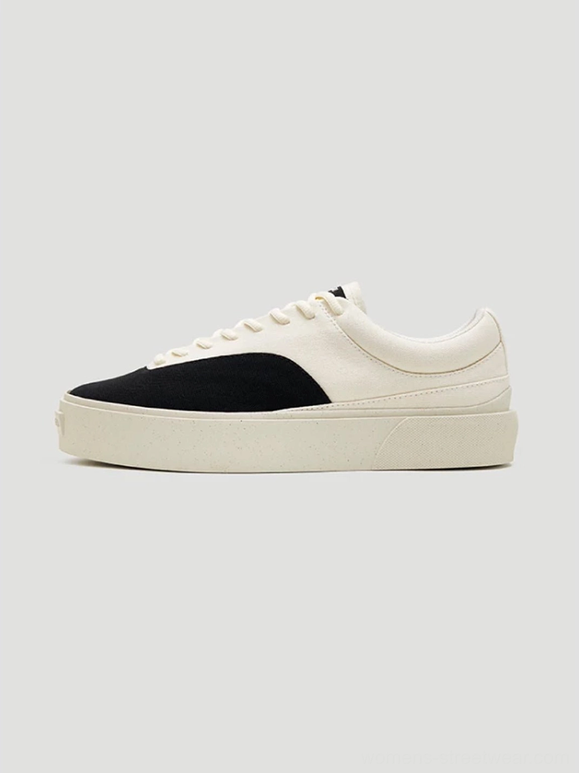 Side view of streamlined egret white and black low-top canvas platform skate sneakers with substantial rubber outsole