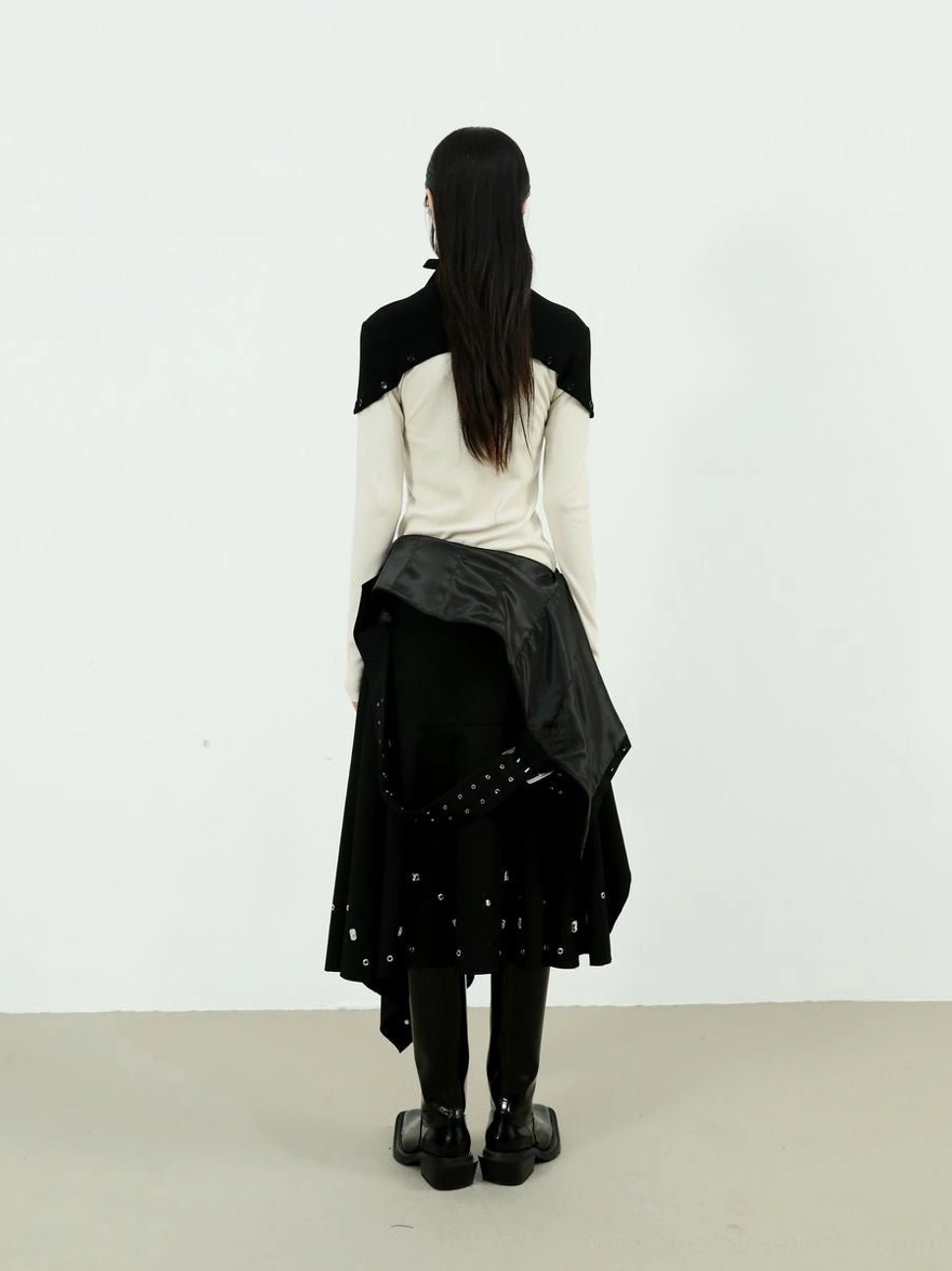 Back view of two-tone high-neck fitted knitwear styled with a black asymmetric skirt and boots