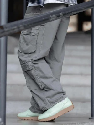Mint green retro runner chunky sneakers styled with gray cargo pants on outdoor concrete stairs
