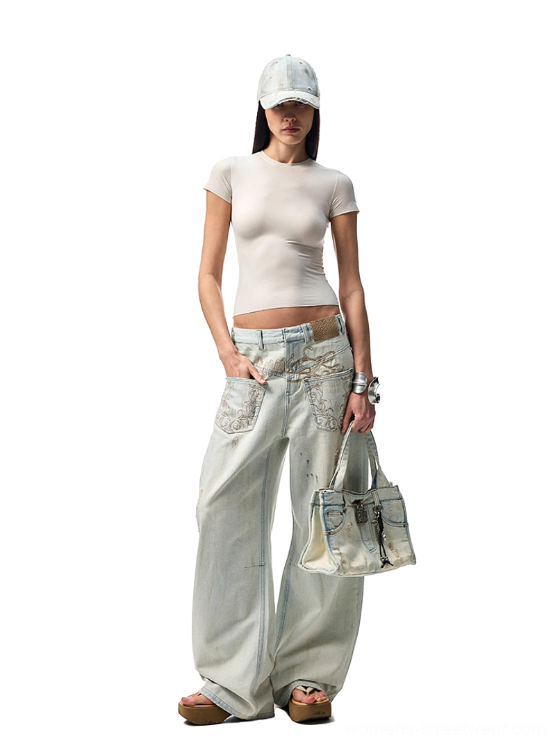 Female model wearing embroidered distressed wide-leg jeans with a cropped fitted tee, baseball cap, and denim tote in a Korean streetwear outfit