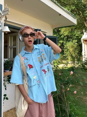 Sky blue embroidered floral waffle shirt with short sleeves and playful text details styled in a relaxed Korean streetwear outfit