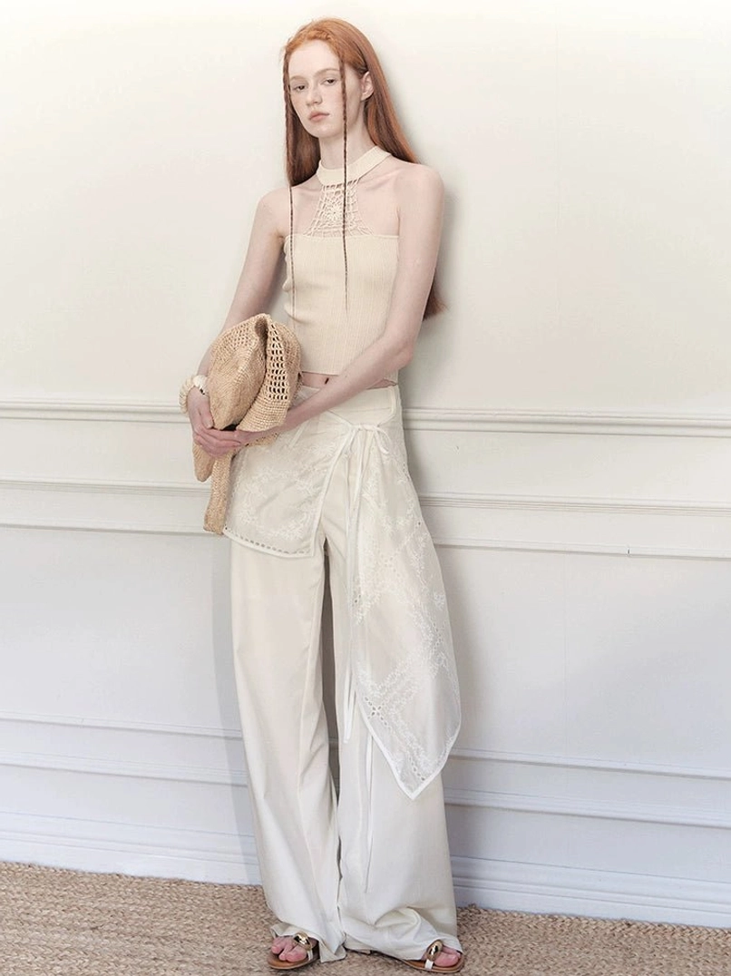 White embroidered wrap skirt wide-leg streetwear trousers styled with a halter camisole in a full-body studio front view
