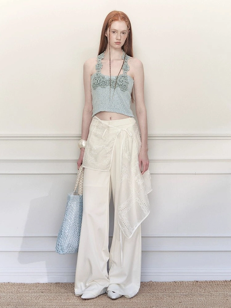 White floral embroidered wrap skirt wide-leg trousers paired with a blue crochet halter top and woven tote bag