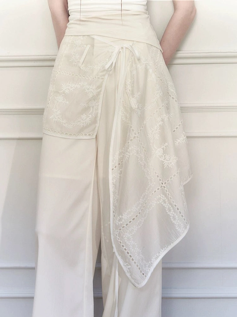 Close back waist detail of white embroidered wrap skirt wide-leg trousers showing floral sheer overlay and adjustable tie