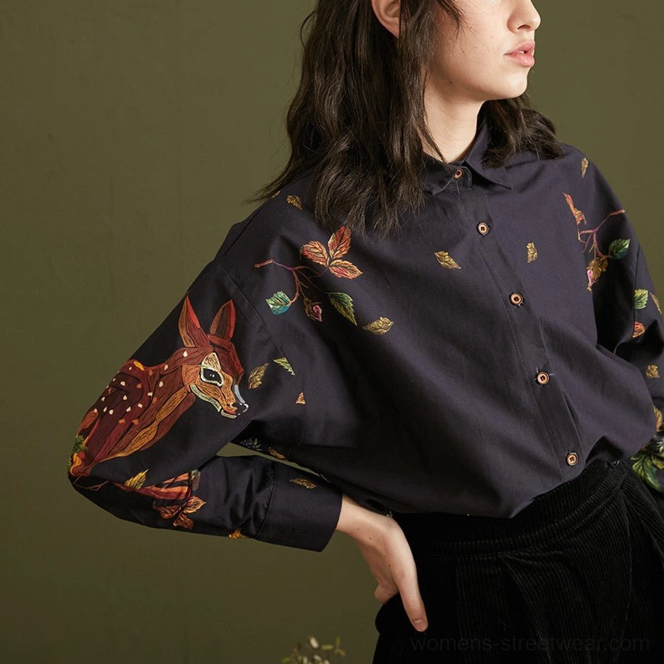 Side view of navy enchanted forest deer and foliage print cotton blouse tucked into high-waisted black pants