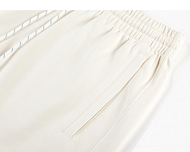 Close-up of apricot cream cotton sweat shorts with ribbed waistband, contrast drawstring, and stitched side pocket