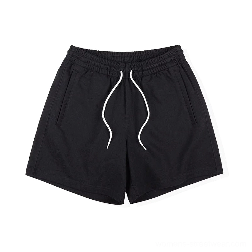 Black relaxed streetwear sweat shorts showing elastic waistband, curved drawstring, and clean side pocket construction