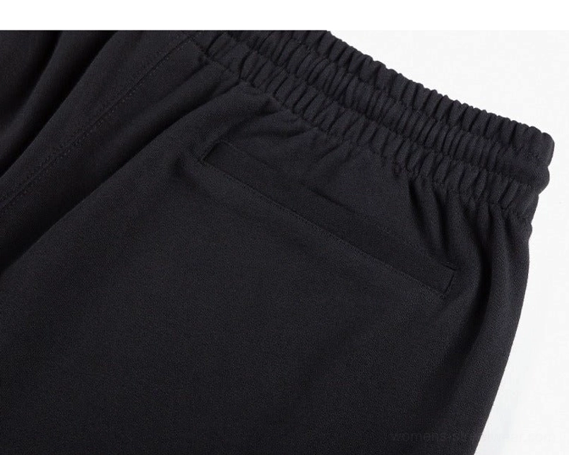 Detailed view of black streetwear sweat shorts elastic waistband, side pocket stitching, and heavyweight knit fabric