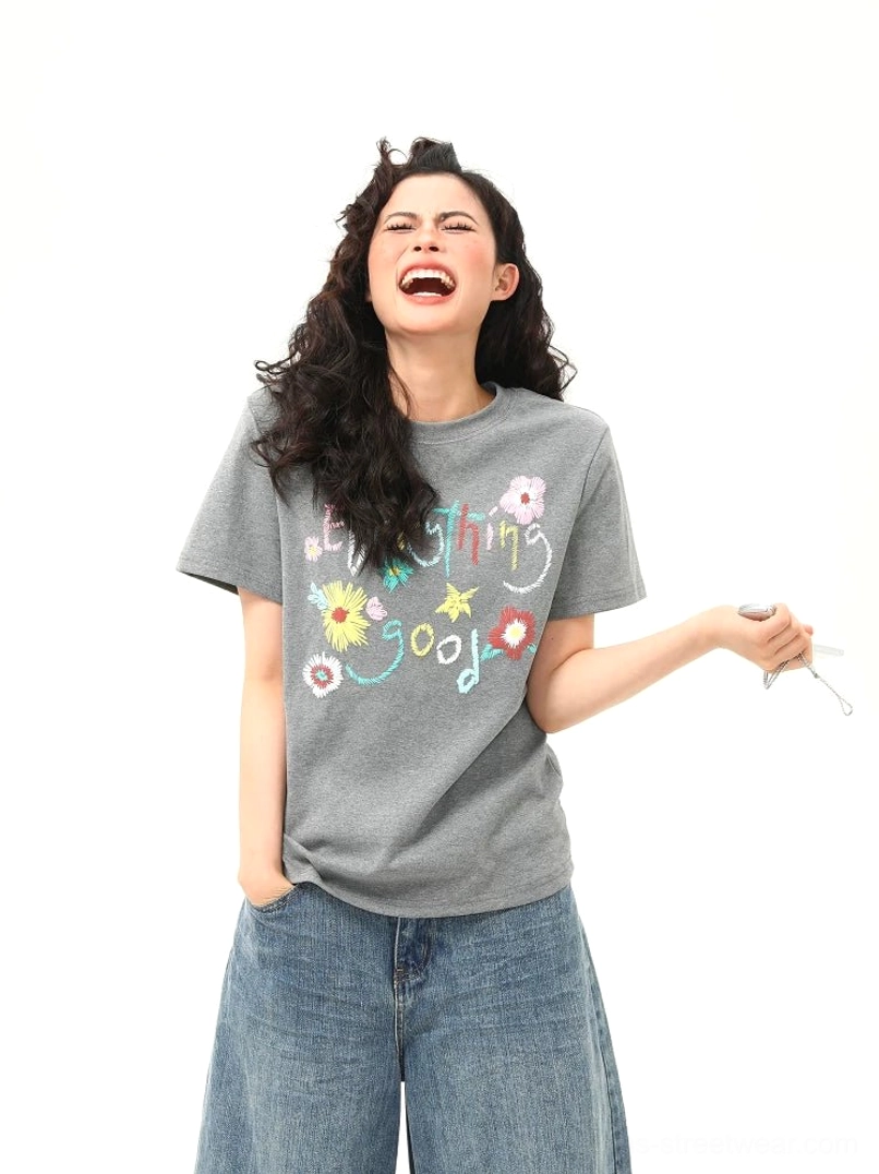 Gray Everything Good floral graphic cotton T-shirt on female model with colorful handwritten lettering, relaxed streetwear fit, and casual denim styling