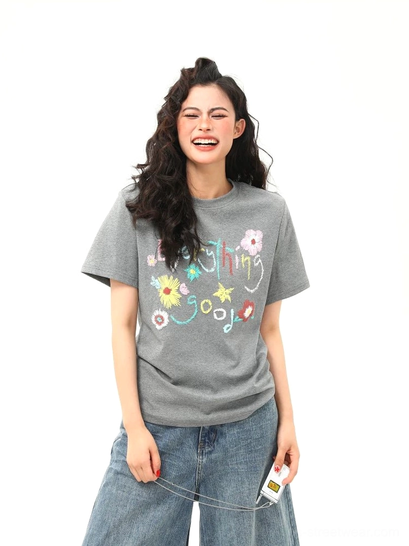 Female model smiling in gray floral graphic cotton T-shirt styled with high-waisted straight-leg jeans for casual Korean streetwear fashion