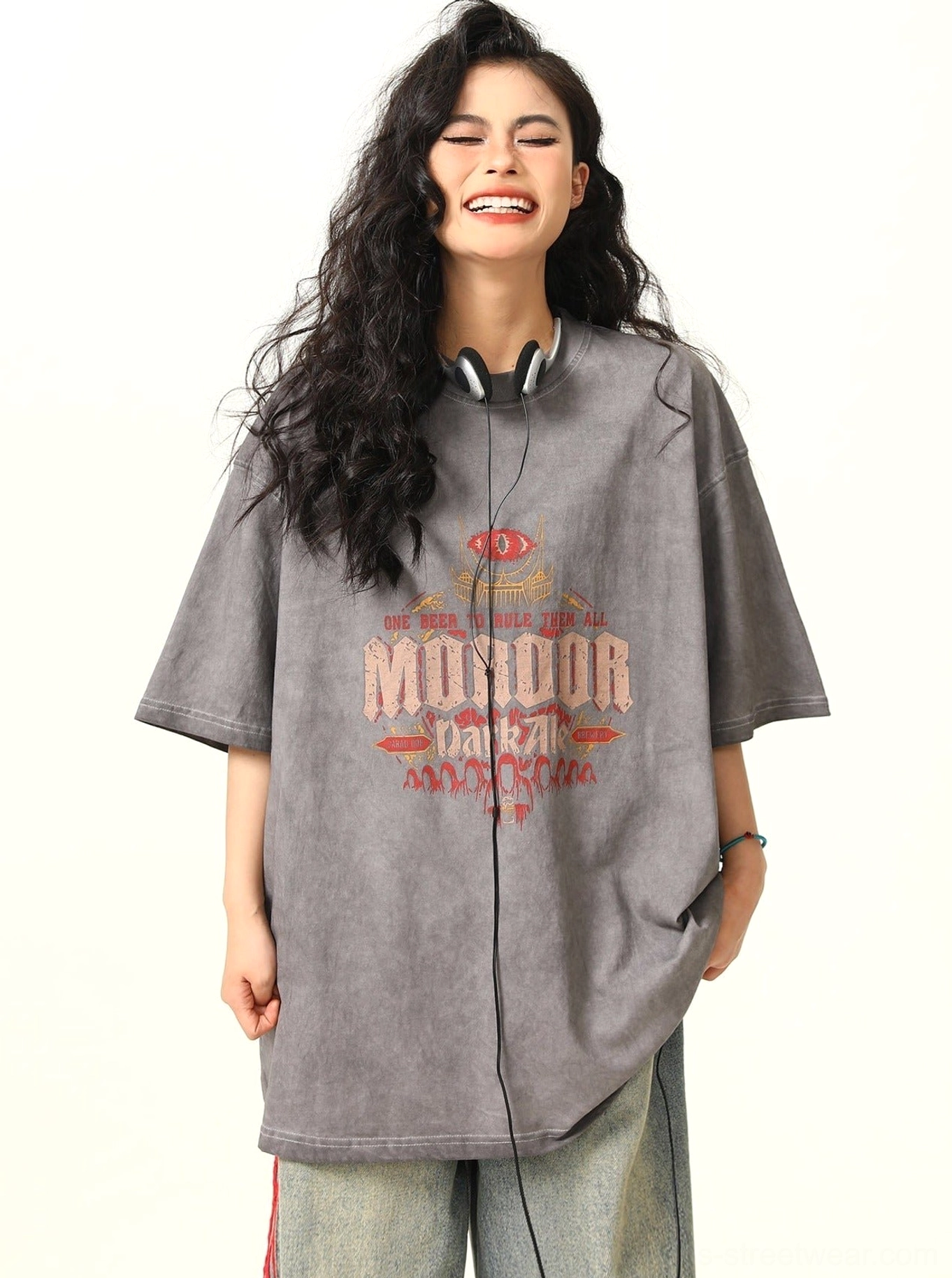 Female model laughing in a faded ash gray MORDOR chest print T-shirt with oversized streetwear fit and relaxed short sleeves
