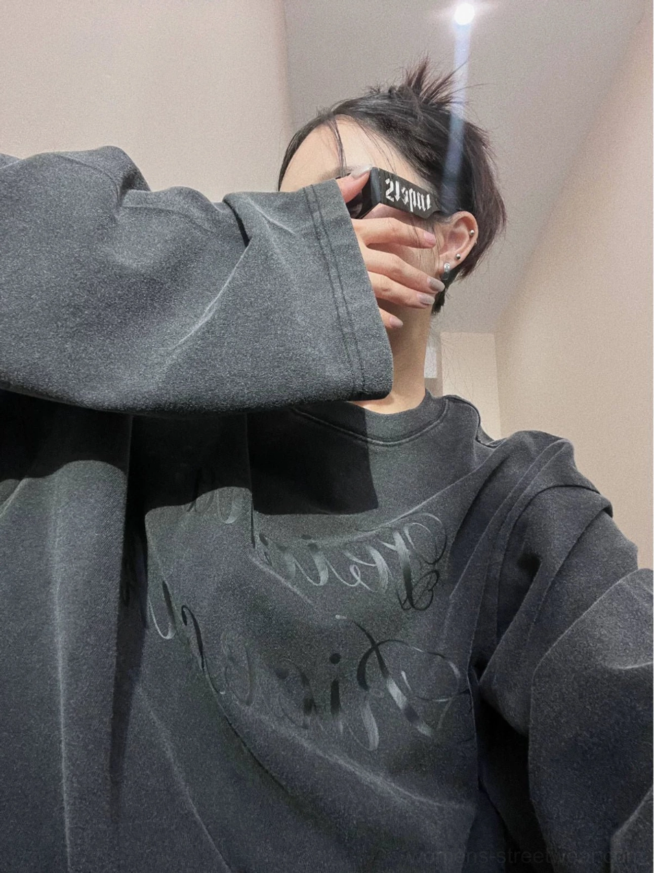 Close-up of wide extra-long sleeves and ribbed neckline on a faded black oversized vintage streetwear crewneck sweatshirt