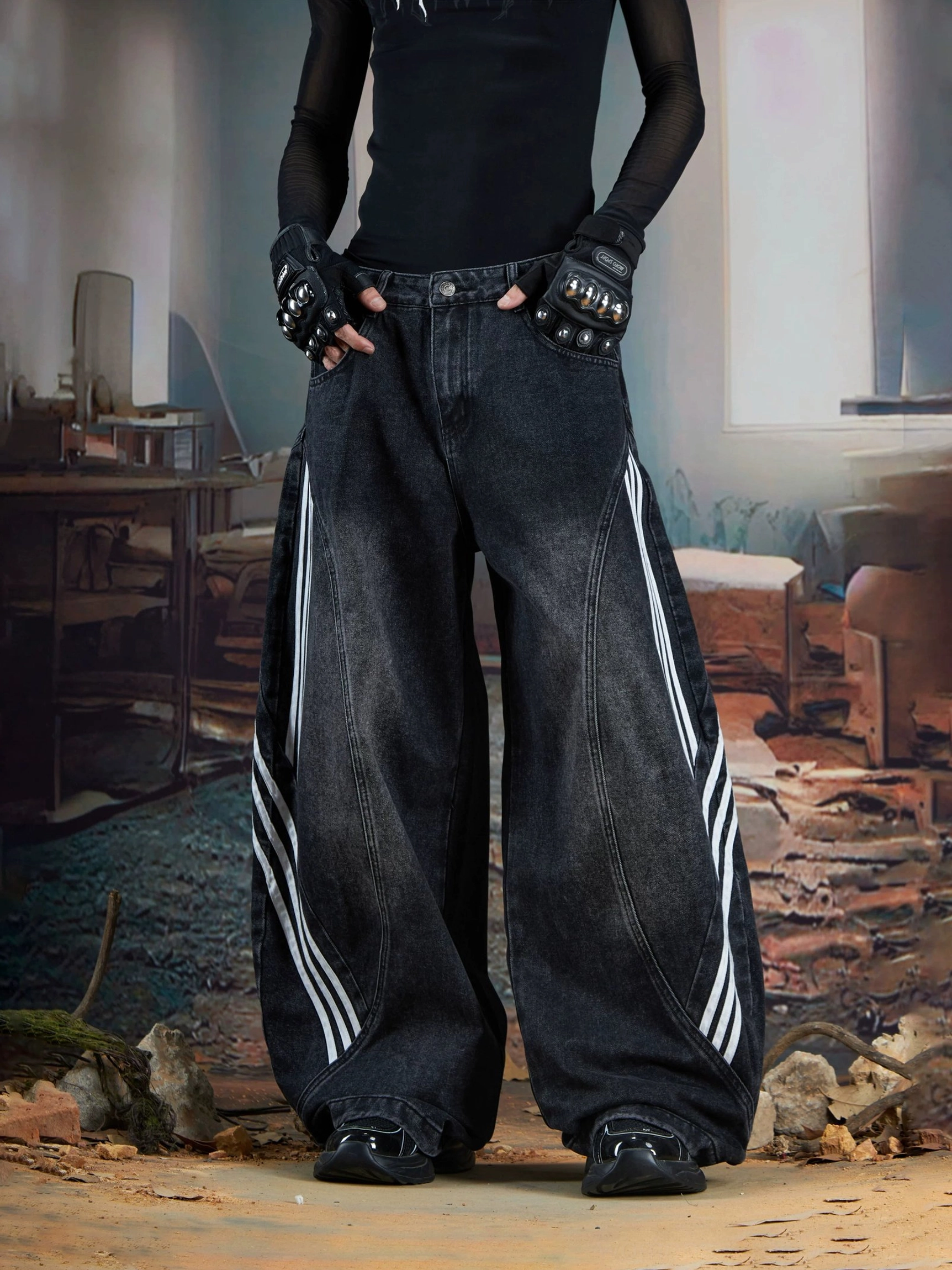 Close-up low-angle view of faded black washed triple-stripe wide-leg denim jeans with bold white stripes and an exaggerated balloon fit