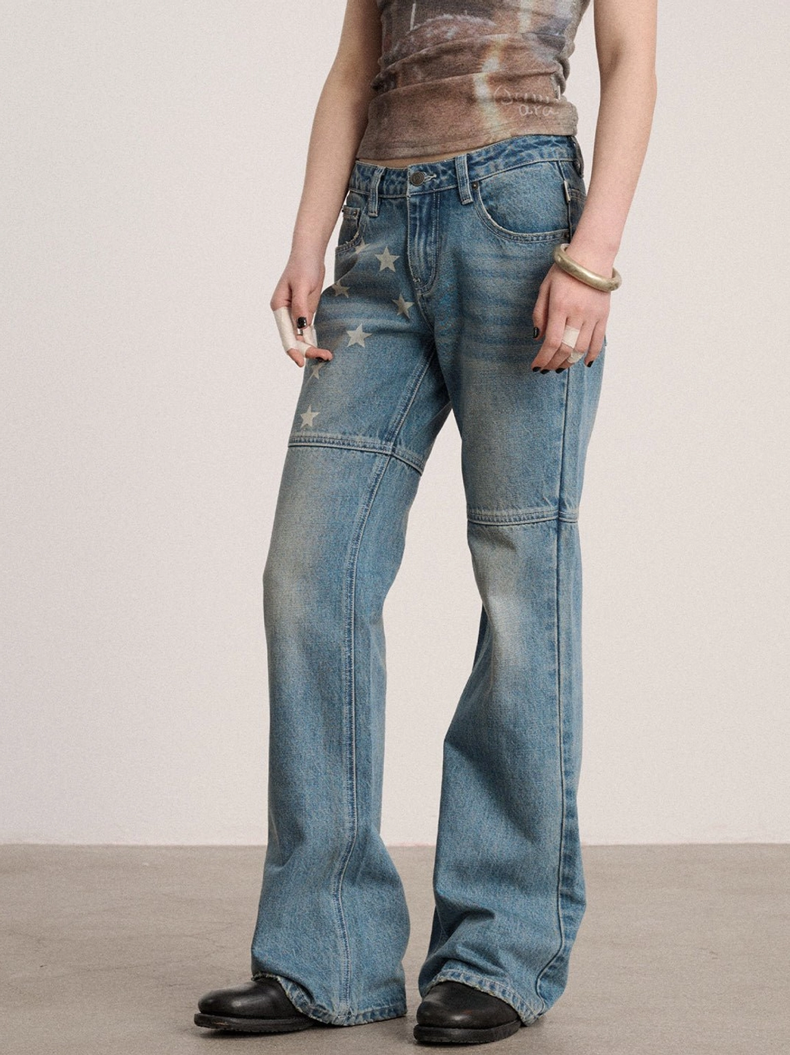 Side view of faded blue low-rise star flare jeans with front thigh graphics, relaxed flared silhouette, and low waistband