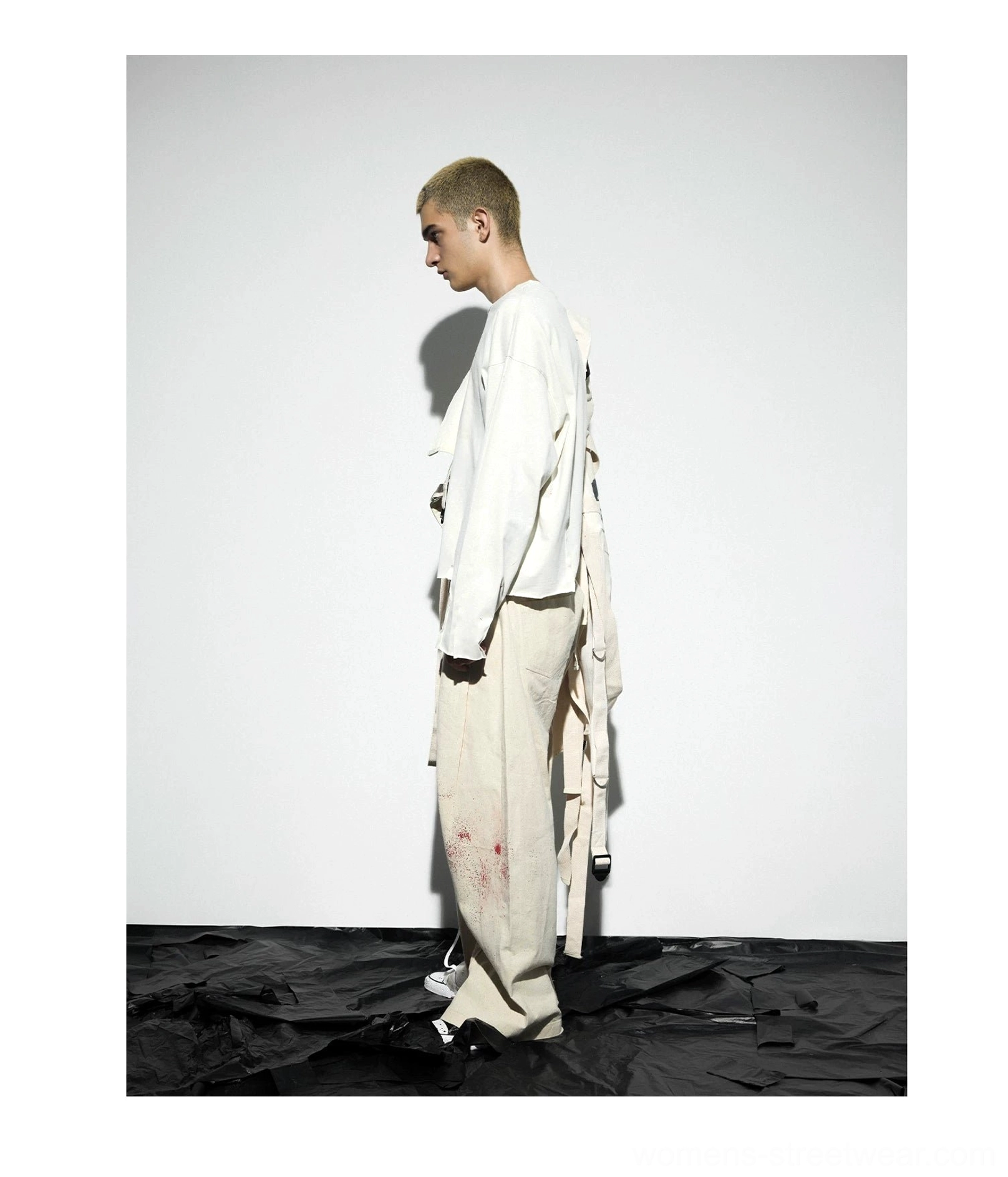 Left side view of distressed oatmeal gray cross graphic long sleeve tee styled with loose cargo pants