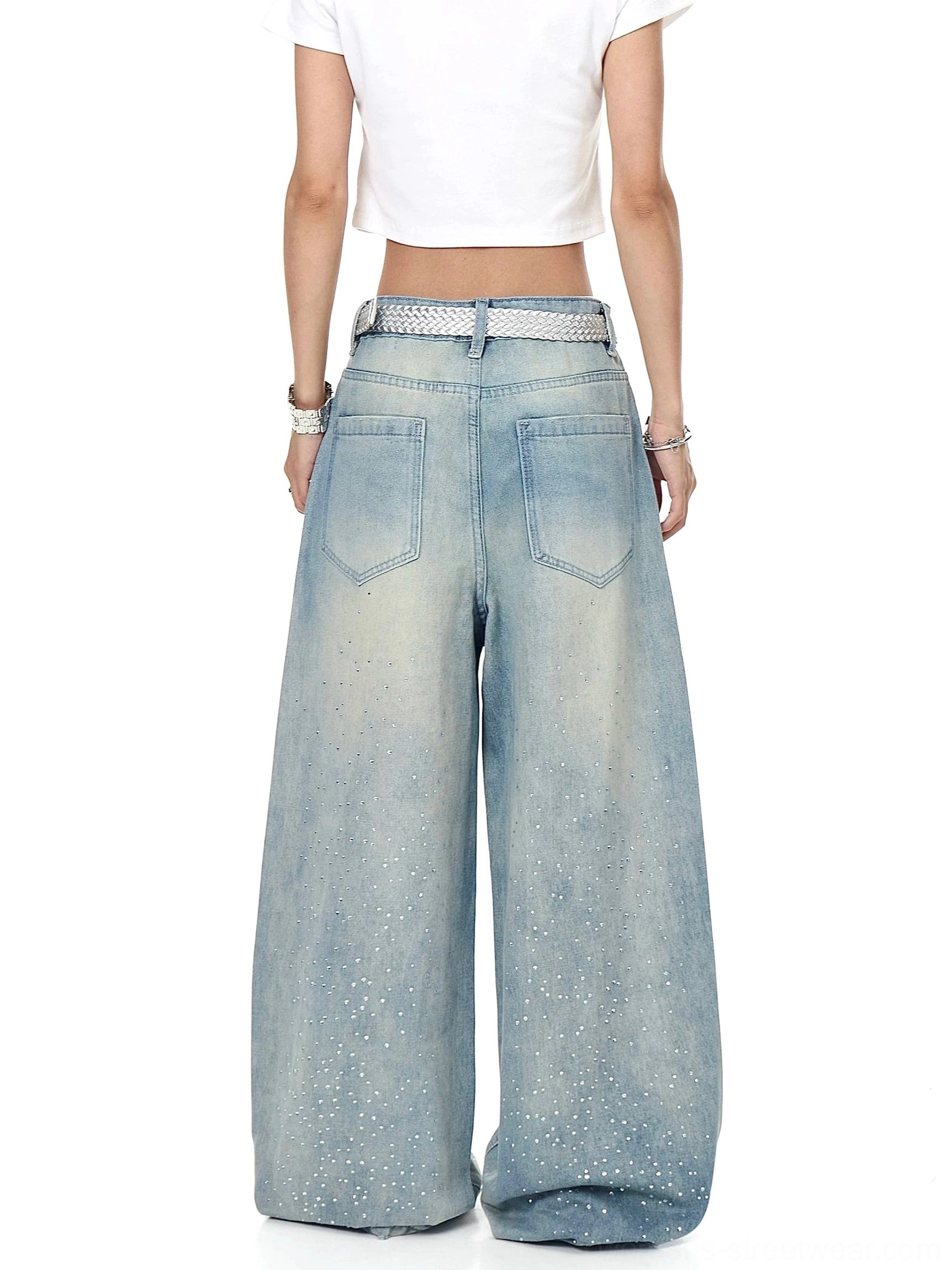 Back view of faded ice-blue oversized wide-leg streetwear jeans with rhinestone outer-leg detailing, classic back pockets, and silver waist belt