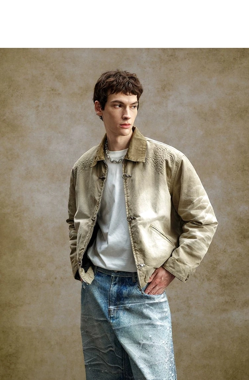Male model styling a faded khaki cotton workwear jacket with metal toggle fastenings, subtle embroidery, and wide-leg denim