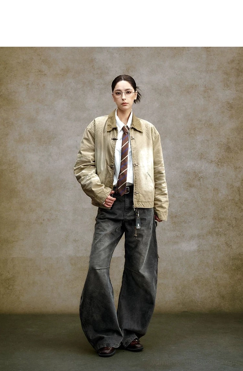 Female model wearing a faded khaki toggle front workwear jacket with contrast collar, relaxed silhouette, shirt, tie, and wide-leg trousers