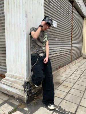 Side rear view of a faded leopard Henley streetwear tee worn with baggy black denim on a city street