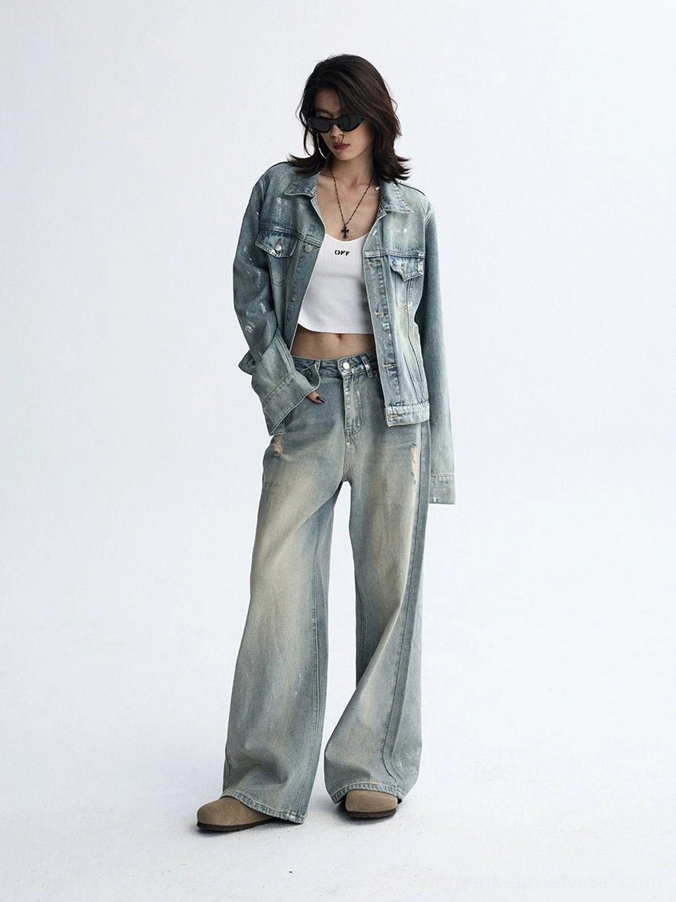 Relaxed vintage streetwear styling with faded light blue wide-leg jeans, classic trucker jacket, and white crop top