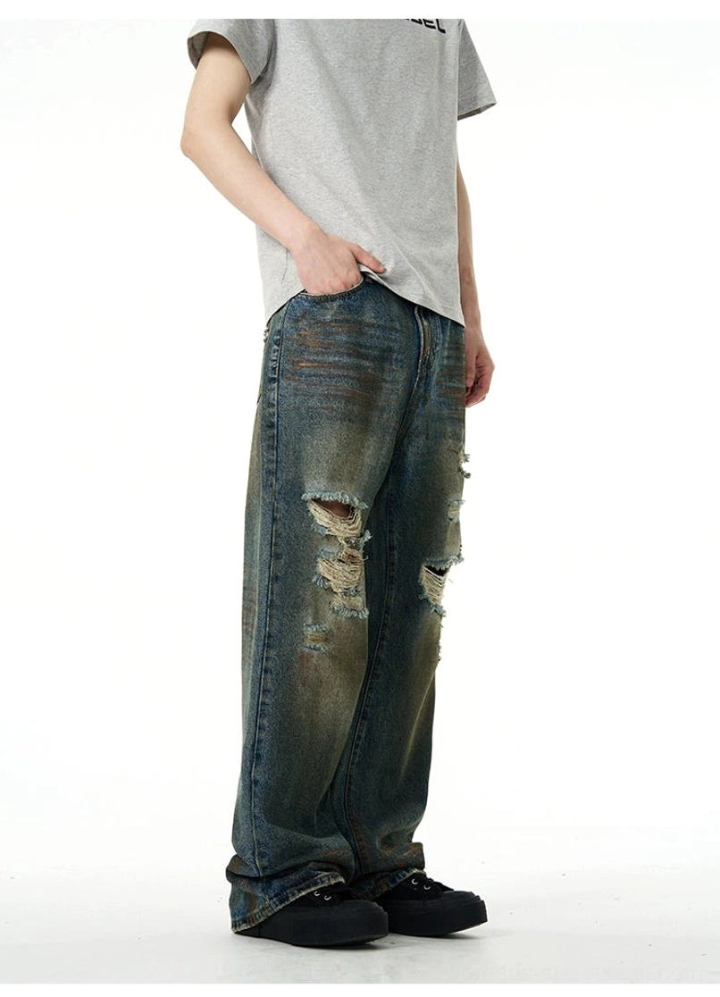 Left side view of vintage faded blue distressed jeans with ripped thighs, ripped knees, and oversized loose-leg silhouette