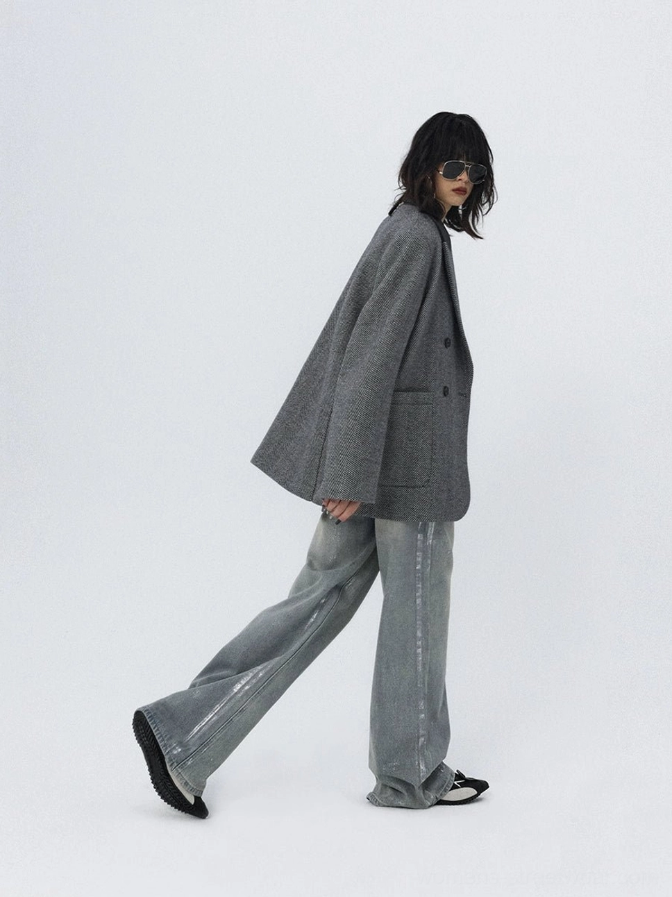 Side walking outfit featuring faded wide-leg jeans, a grey blazer, distressed denim details, and relaxed off-duty street style