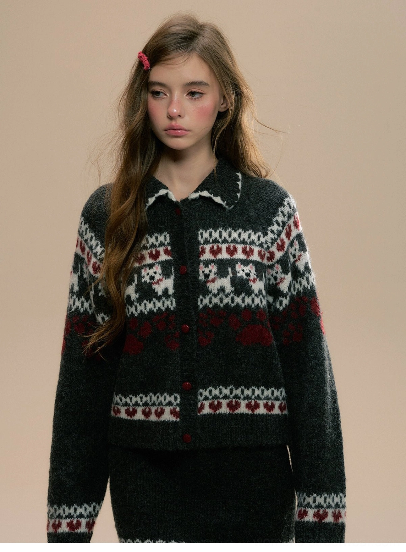 Close-up of Fair Isle knit cardigan collar with cat and heart jacquard pattern, wine-red buttons, and red hair accessory