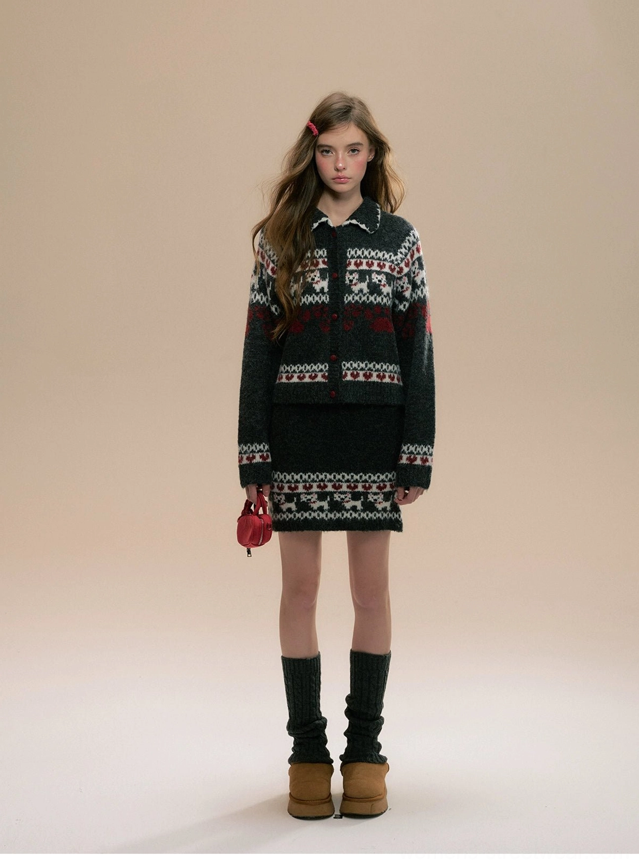 Front view of dark charcoal Fair Isle knit cardigan and mini skirt set with cat heart jacquard motifs, red handbag, black knee-high socks, and tan platform boots