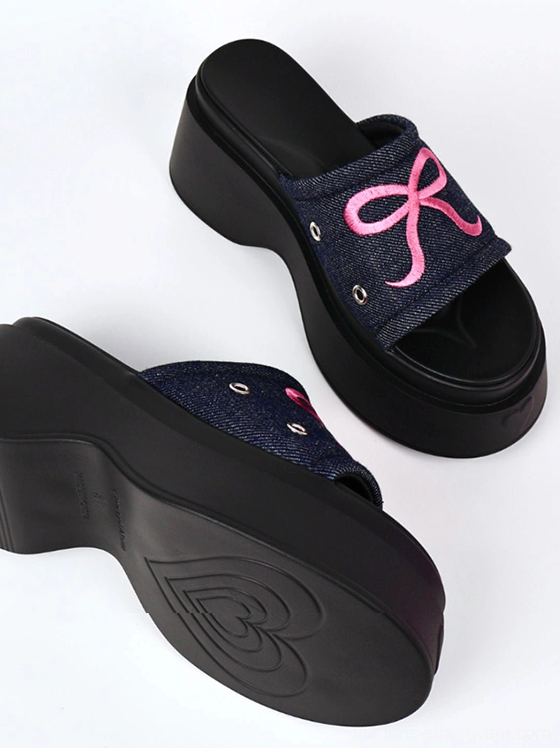 Fashion-forward hot pink and black bow sandals with a bold sculpted platform sole for women