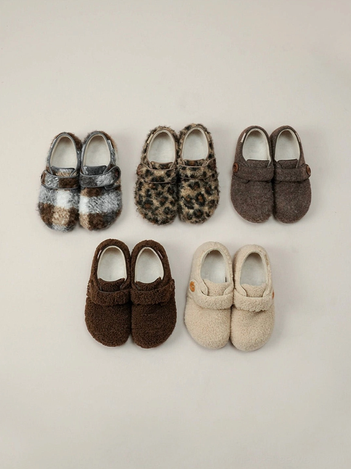 Collection of faux fur Velcro slip-on shoes in leopard plaid coffee and neutral colorways arranged in a streetwear flat lay