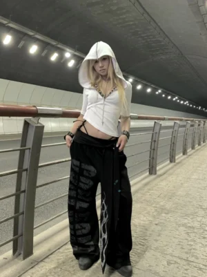 Blonde model wearing black fight night flame graphic wide leg streetwear sweatpants in an urban tunnel setting