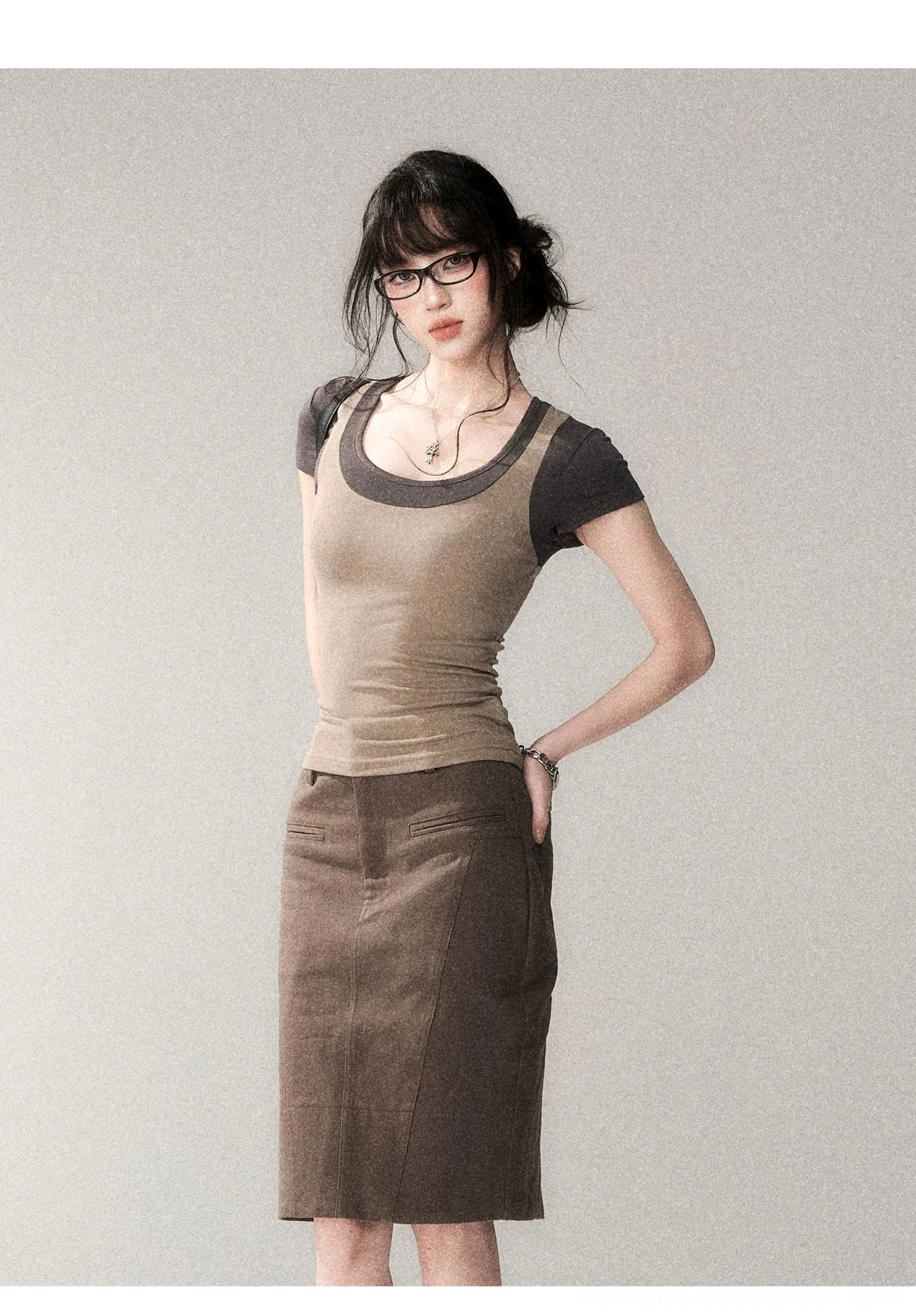 Side profile of a slim fitted layered scoop neck Korean streetwear top with contrasting trim, styled with a brown midi skirt and black frame glasses