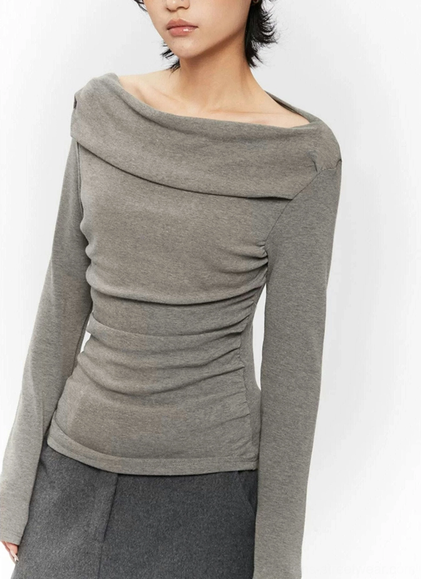 Close-up fashion detail of a fitted off-shoulder ruched top with gathered texture and draped neckline