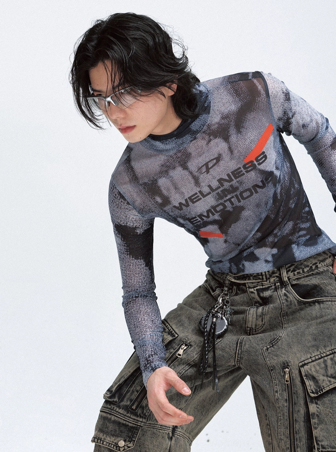 Close-up side view of a fitted sheer black mesh long-sleeve turtleneck with graphic print and cargo denim styling