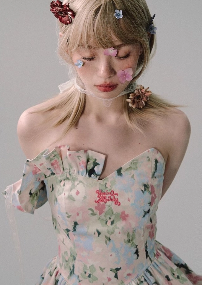Close-up front view of a fitted watercolor floral mini dress with sweetheart neckline, corset-inspired bodice, removable ruffle sleeves, and pastel print