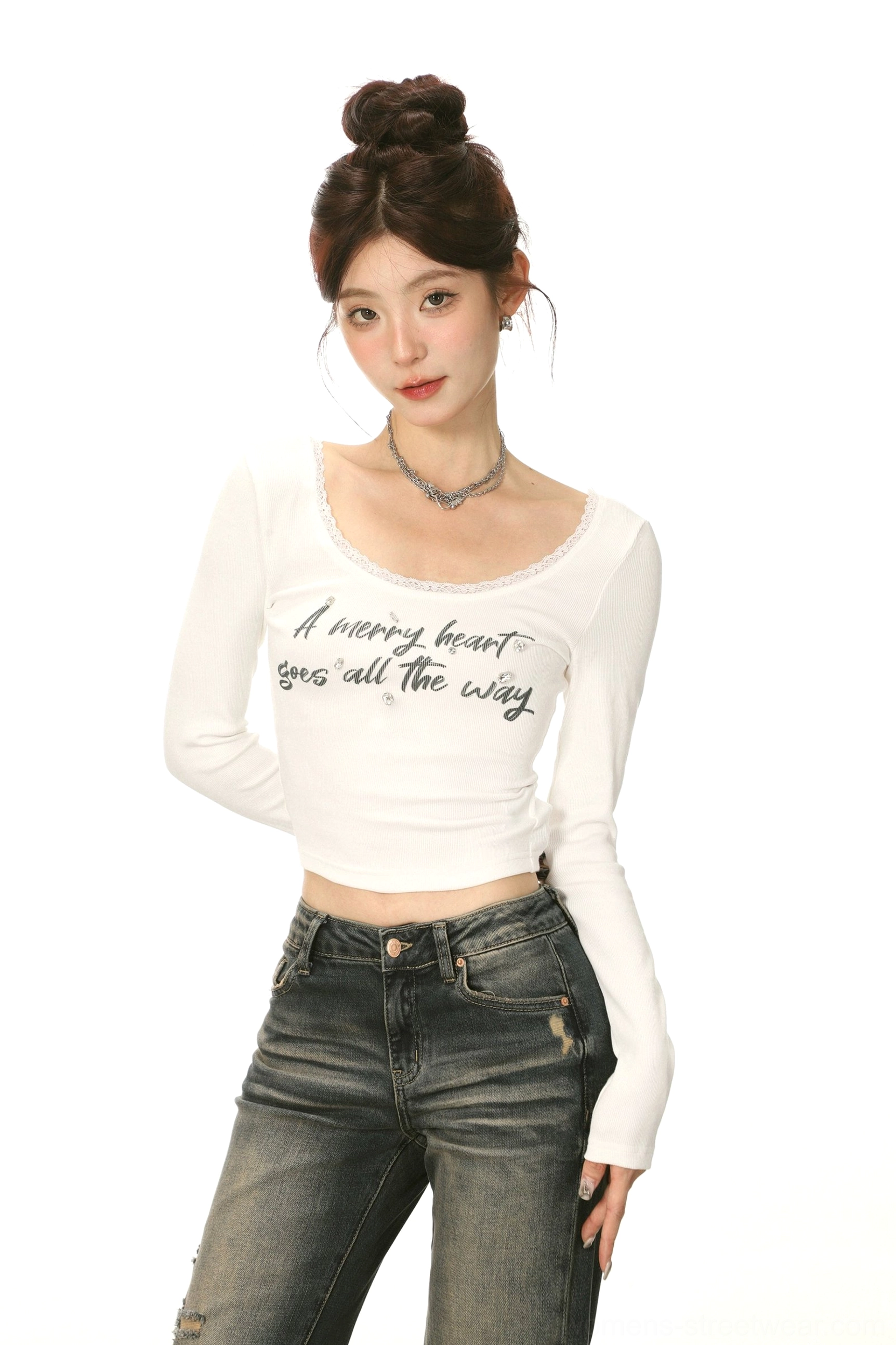 Close-up view of a fitted white cropped U-neck long-sleeve top with delicate lace neckline and low-rise vintage denim styling