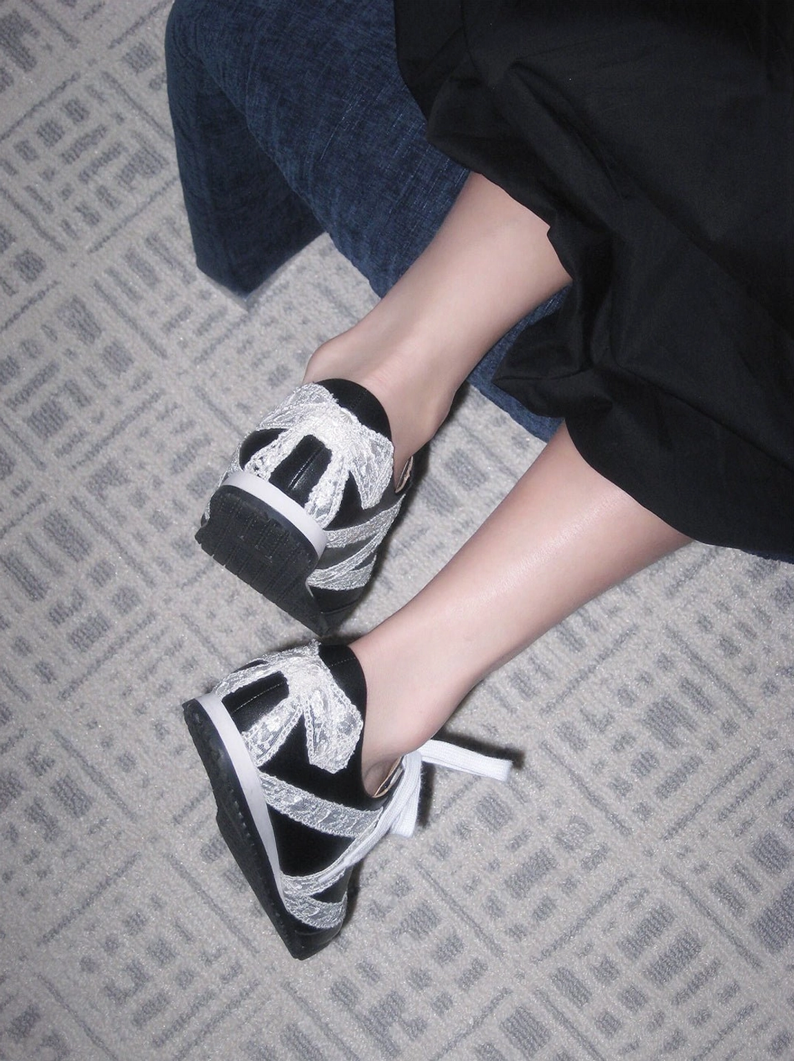 Top view of black and white floral lace microfiber leather sneakers showing white laces and bow heel decorations