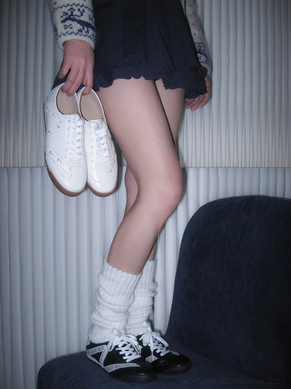 Model wearing black and white floral lace low-profile sneakers while holding the all-white sneaker colorway