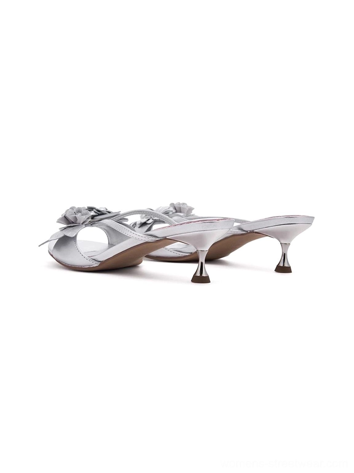 Floral metallic silver kitten heel slide sandals for women with crisscross straps, sculptural flower accents, and elegant contemporary styling